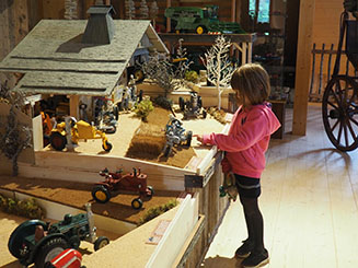 Une enfant émerveillée devant une ferme miniature
